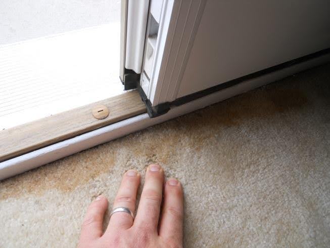 Photo on right shows water-stained carpet. I would warn a client about risks of hidden water damage with these visible red flags. This house was built in 2006. This door appeared to be installed with correct threshold orientation but was still leaking – perhaps a faulty sweep design? Note the flat sill outside – a likely problem.  
