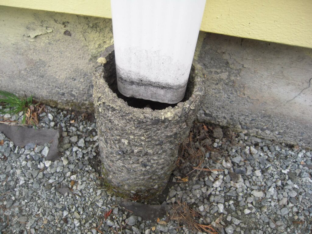 A gutter draining into a concrete pipe. Useful to prevent moisture damage around a house